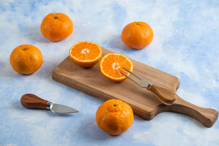 Pile of mandarins. Whole or half cut on wooden cutting boardの写真素材