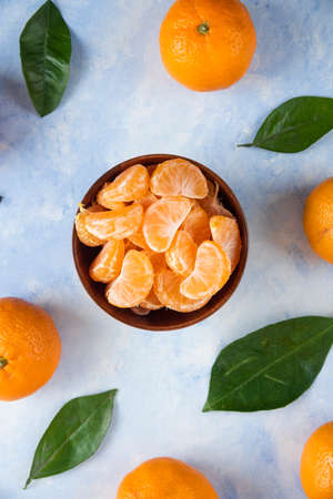 Top view of sliced and whole mandarins on blue backgroundの写真素材