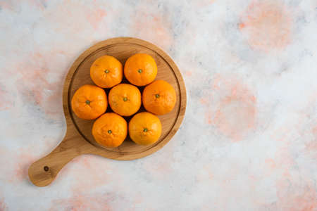 Pile of clementine mandarins over wooden cutting boardの写真素材