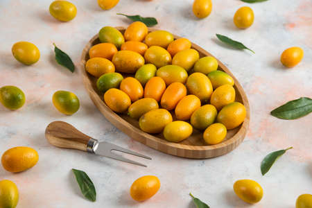 Close up photo, Pile of kumquats on wooden plateの写真素材