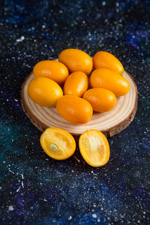 Vertical photo of kumquats over wooden boardの写真素材