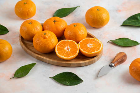 Clementine mandarins and leaves on wooden plateの写真素材