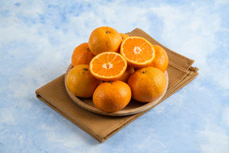 Pile of clementine mandarin n wooden plate over towelの写真素材