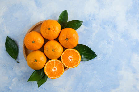 Top view of clementine mandarins with leaves on wooden plateの写真素材