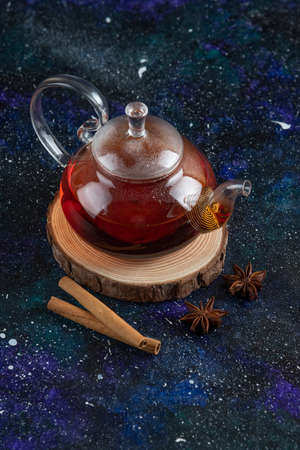 Vertical photo of Glass tea pot with cinnamon on wooden boardの写真素材