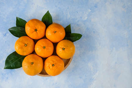 pile of clementine mandarins and leaves on wooden plateの写真素材