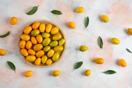 Top view, Pile of kumquats on wooden plate over colorful background