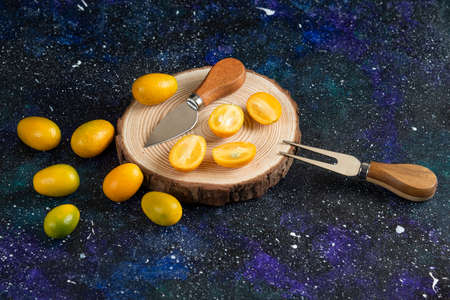 Pile of kumquats whole or half cut over wooden boardの写真素材