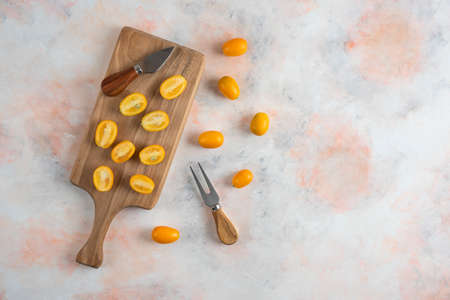 Top view of kumquats whole or half cut on wooden board