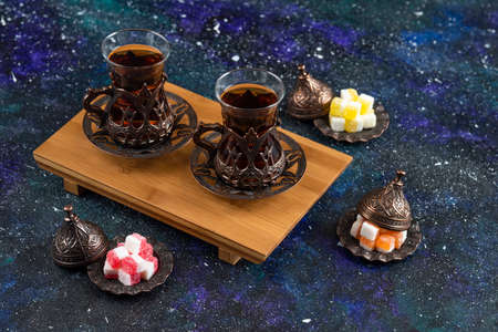 Top view of Two glass tea on wooden board and candies on blue backgroundの写真素材
