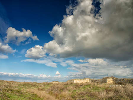 Dramatic blue sky with white clouds over the ruins of the ancient greek colony of Histria, on the shores of Black Sea. Histria is the oldest urban settlement on Romanian territoryの写真素材