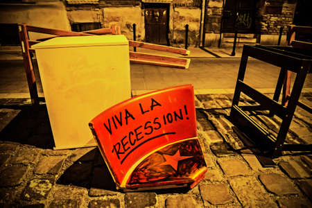 thrown out seat with viva la recession writing and a red star at night in street in Budapestの写真素材