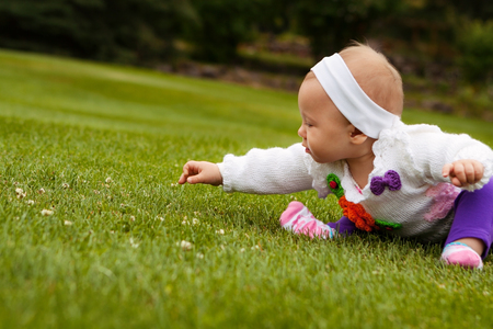 Beautiful baby girl playing on grass fieldの写真素材