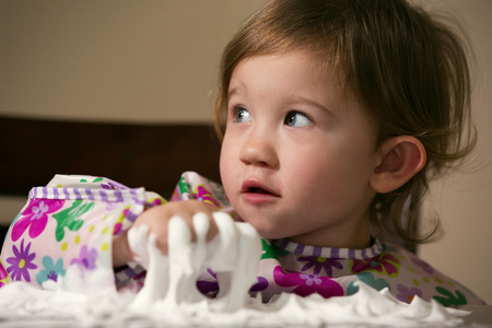 Little girl enjoying playing with foamy creamの写真素材