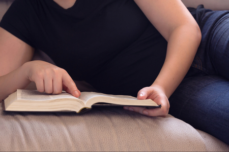 Young woman relaxing on the couch reading the Bible