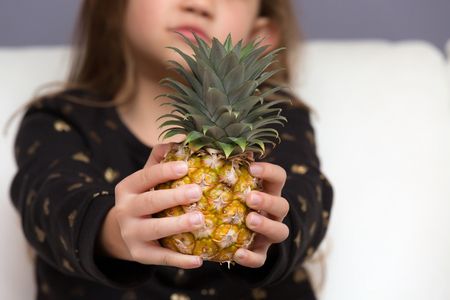 A Little Girl Holding Organic Healthy Pineapple Fruitの写真素材