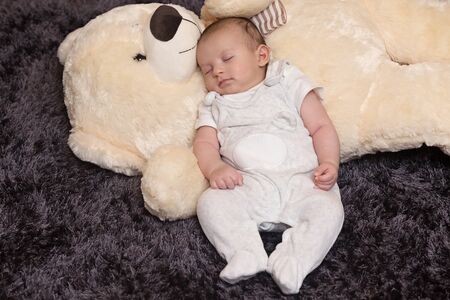 Peaceful newborn sleeping with giant fluffy teddy bear