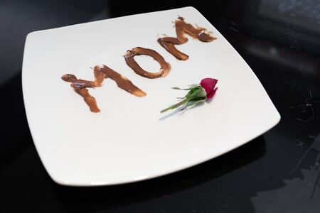 The word mom written on a plate with chocolate spread by her young daughterの写真素材