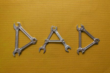 The word dad spelled out with wrenches on a Mustard Yellow backgroundの写真素材