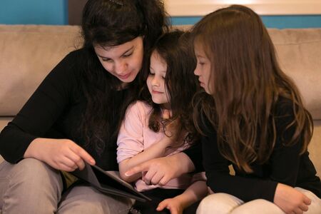 Young Mother teaching children at home on Electronic Device