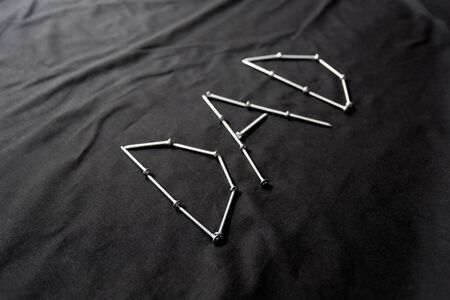 The Word Dad Spelled Out With Screws on a Black Backgroundの写真素材