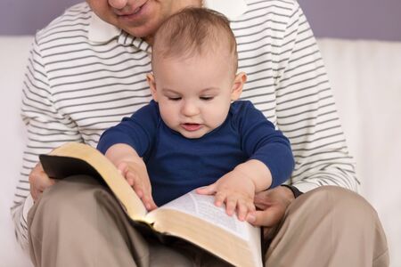 Grandad reading stories from the Holy Bible to his young grandsonの写真素材