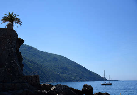 Seascape view with rocky beach and a sailing boat floating on the sea