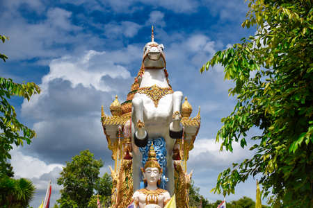 Kanchanaburi, Thailand 08.17.2019: Statue of Deity, god or goddess riding a detailed, ornately decorated white horse tracking a golden boat at the Wat Chai Chumphon Chana Songkhram templeのeditorial素材