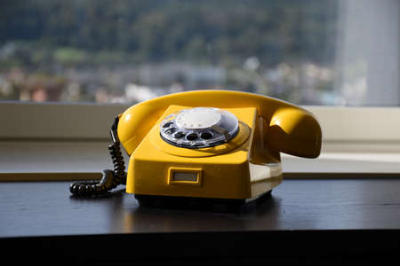 Old Retro Vintage Yellow Rotary Telephone on black wood tableの写真素材