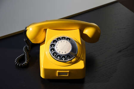 Old Retro Vintage Yellow Rotary Telephone on black wood tableの写真素材