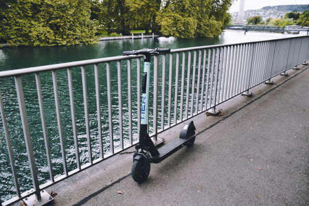 Zurich, Switzerland, 11.14.2019: Modern, electric TIER shared scooter leaning on the railings of the pedestrian sidewalk on the riverside of the Limmat river in Zurichのeditorial素材