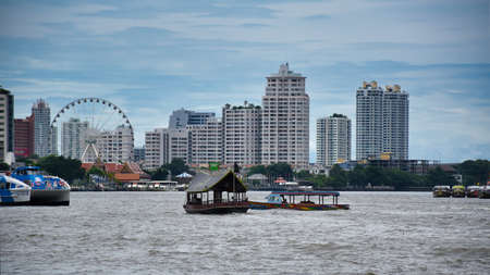 Bangkok, Thailand .11.24.2019: Cityscape view of Bangkok with boats on the Chao Phraya River and with the Asiatique Sky Ferris wheel of the Asiatique The Riverfront large open mall in the backgroundのeditorial素材