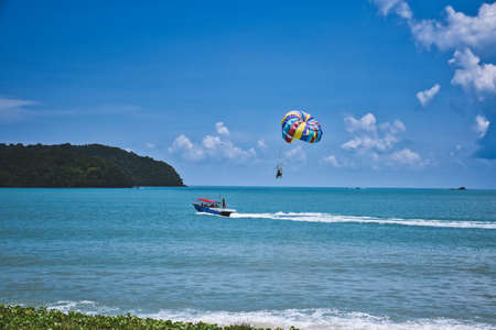 Parasailing on the waves of the azure Andaman sea under the blue sky near the shores of the sandy...