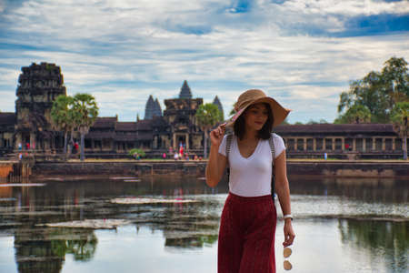 Beautiful, pretty, young Thai girl is exploring the ancient ruins of Angkor Wat (City/Capital of Temples) Hindu temple complex in Siem Reap, Cambodia. The largest religious monument in the worldの写真素材