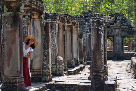 Beautiful, pretty, young Thai girl is exploring the ancient ruins of Angkor Wat (City/Capital of Temples) Hindu temple complex in Siem Reap, Cambodia. The largest religious monument in the worldの写真素材