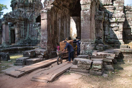 Siem Reap, Cambodia - February 15, 2020: Cambodian people carrying a giant sandstone during the renovation of the Preah Khan Temple site among the ancient ruins of Angkor Wat Hindu temple complex in Siem Reap, Cambodiaのeditorial素材