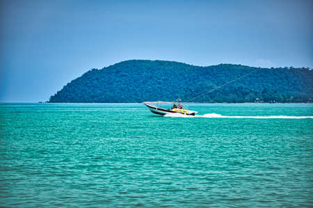Langkawi, Malaysia, 11.09.2019: Speed boat on the waves of the azure Andaman sea under the blue sky near the shores of the sandy beautiful exotic stunning Cenang beach in Langkawi island, in Malaysia.のeditorial素材
