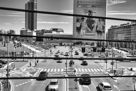 Milan, Italy, 06.29.2020: View of crossroads through the iron wires of a pedestrian bridge. Futuristic, luxury apartments and offices within the new Milanese pole of innovation and business of Porta Nuovaのeditorial素材