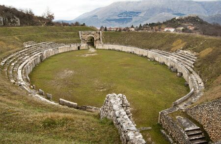View of ancient Roman Amphitheater at Alba Fucens, Italy, dating the first half of the first century AD, with the ruined medioeval village and castle on the top background.のeditorial素材