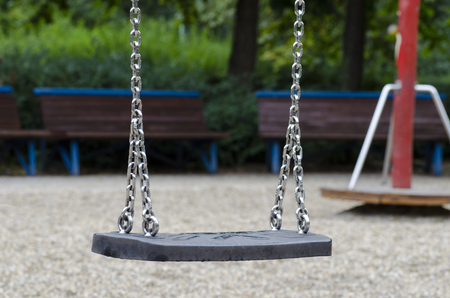 picture of a children's swing with iron chains on a playground during an autumnal rainy dayの写真素材