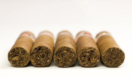 Close-up photo of still life with five cigars on white table with blurred backgroundの写真素材