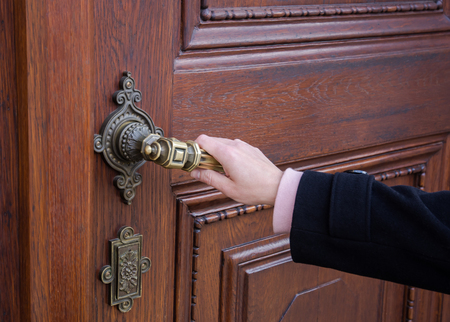 A female hand holding a crank from an old wooden door and openingの写真素材