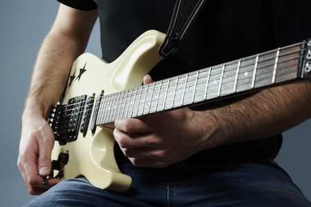 Hands of a young man holding a electric guitar
