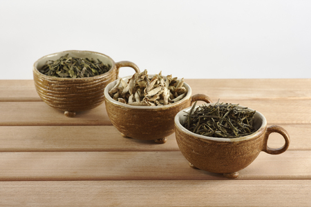 Three cups with green and white tea leaves on a white backgroundの写真素材