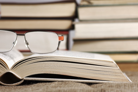 An open book with glasses lying on a jute mat with a blurred backgroundの写真素材