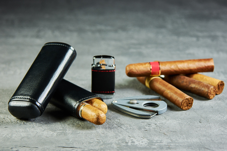 Six Cuban cigars on a stone table with a lighter, cutter and a leather case.の写真素材