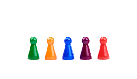Five plastic toys - playing pieces with different colors as diverse team standing in a row - isolated on white backgroundの写真素材