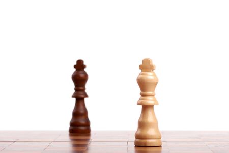 Two wooden chess pieces, black and white king on the board. Strategy and victory isolated on white background.の写真素材