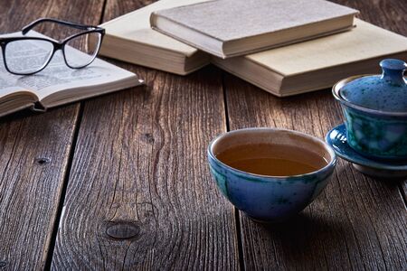 Still life with old wooden table, mug or cup of tea and books.の写真素材