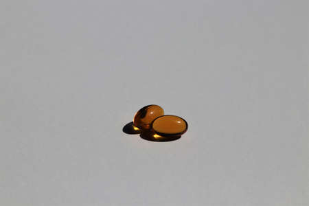Two fish oil capsules on plain white background